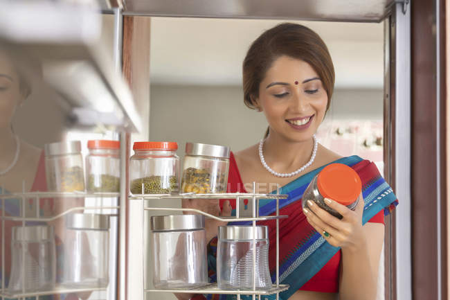 Жінка на кухні виймає банку з кабінету — стокове фото