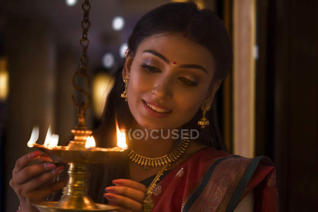 Young woman lighting a lamp — Stock Photo