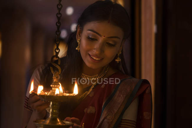 Young woman lighting a lamp — Stock Photo