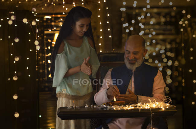 Grand father and grand daughter preparing diyas together — Stock Photo