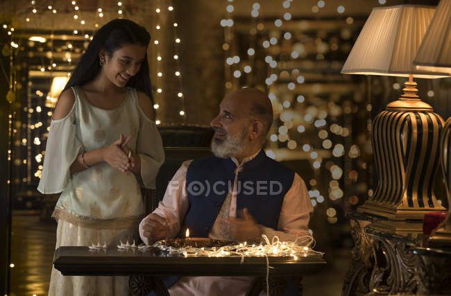 Grand father and grand daughter preparing diyas together — Stock Photo