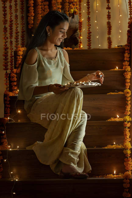 Young girl sitting on stairs with diyas — Stock Photo