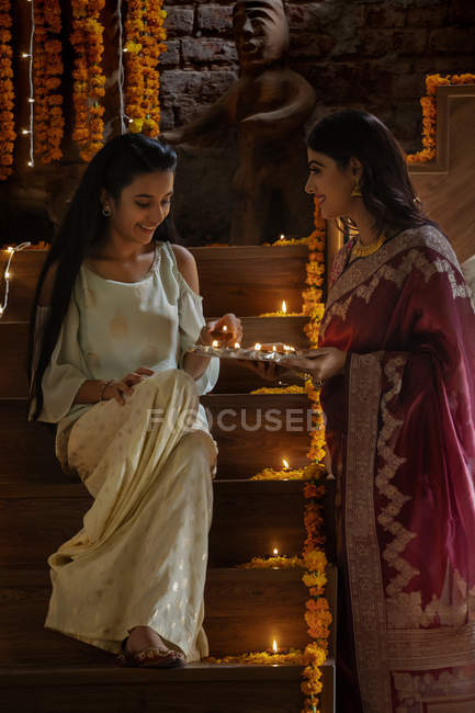 Mother and daughter decorating stairs with diyas on diwali — Stock Photo