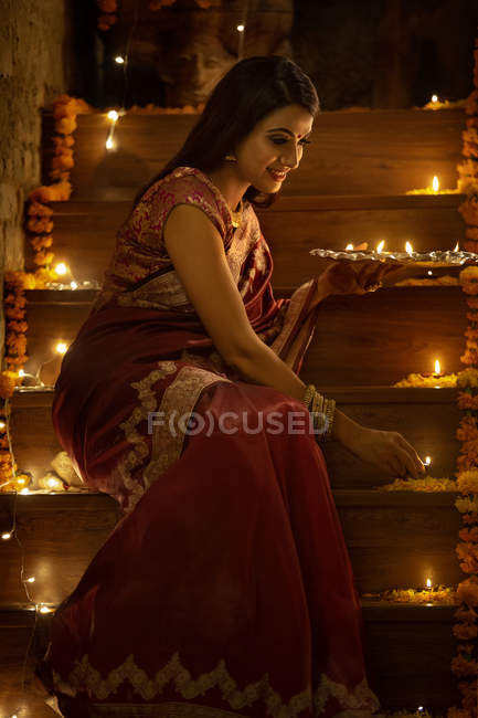 Young woman decorating stairs with diyas on diwali — Stock Photo