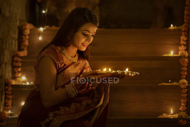 Young woman sitting on stairs with diyas in hand — Stock Photo