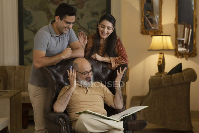 Pai, mãe e filho estão a olhar para um livro e a sorrir. (Família ) — Fotografia de Stock