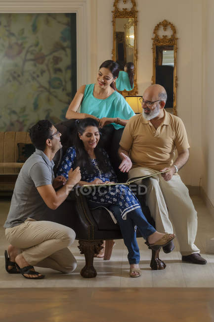 Eine Familie schaut in ihrem Wohnzimmer auf ein Fotoalbum und lächelt. — Stockfoto