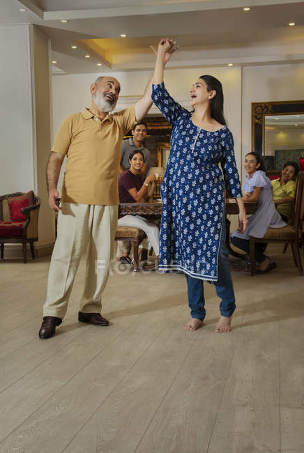Los abuelos bailan en la sala de estar frente a la familia . - foto de stock