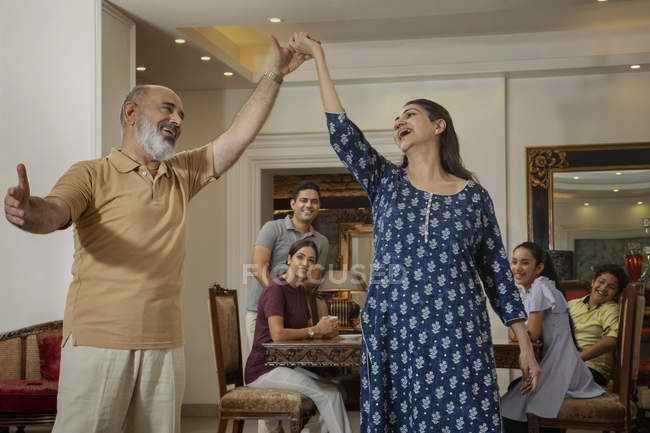 Großeltern tanzen im Wohnzimmer, während die Familie zuschaut. — Stockfoto