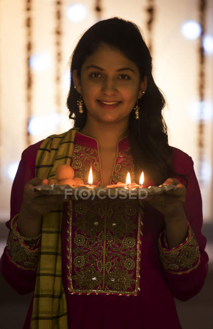 Portrait of a young woman standing in office with a tray of diyas during Diwali celebrations. — Stock Photo