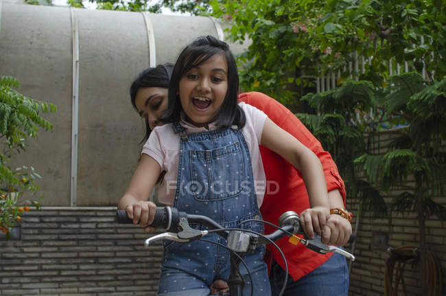 Мать помогает дочери ездить на велосипеде — стоковое фото