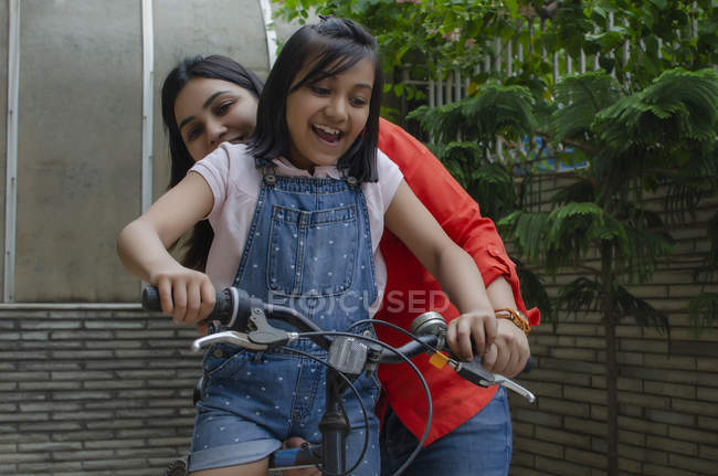 Madre ayudando a hija montar en bicicleta - foto de stock