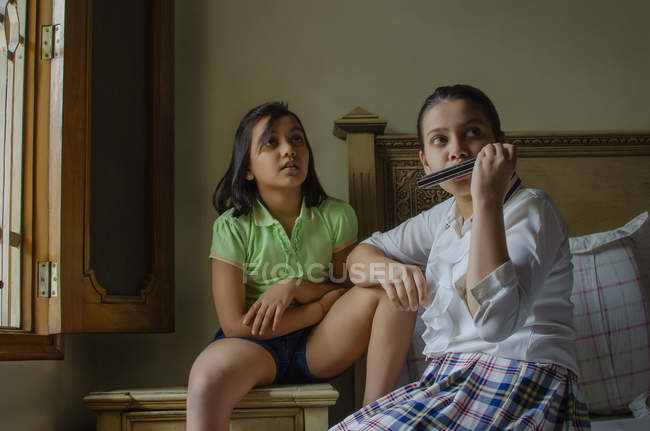 Mädchen sitzen zusammen und spielen Mundharmonika — Stockfoto