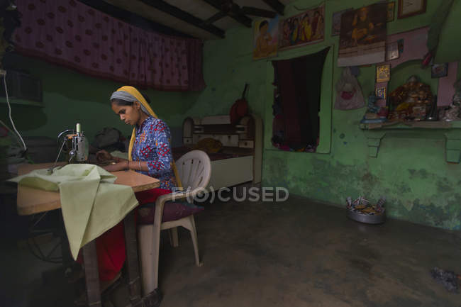 Young girl stitching clothes in her hut — Stock Photo