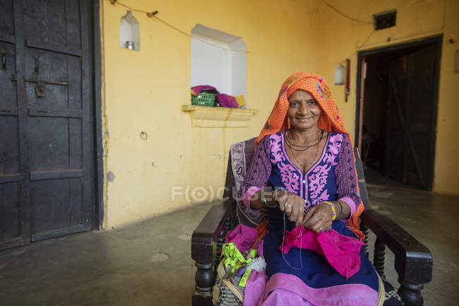 Mulher velha costura pano em sua casa — Fotografia de Stock