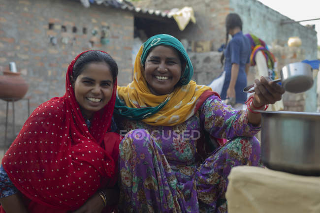 Mère et fille souriant, tout en faisant du thé dans la cour de leur maison — Photo de stock