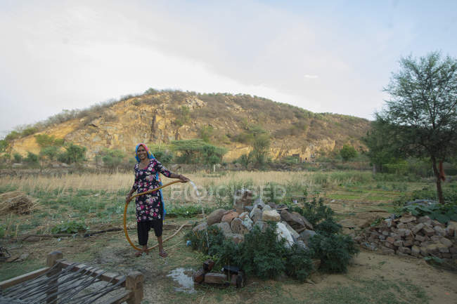 Frau gießt Pflanzen mit einem Rohr, auf dem Feld — Stockfoto