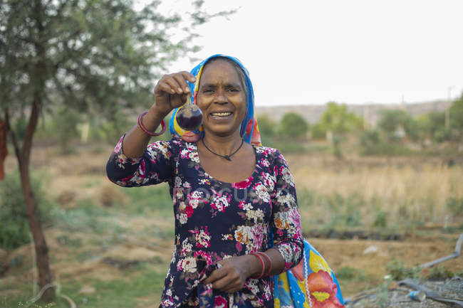Donna che tiene brinjal e sorridente, nel campo — Foto stock