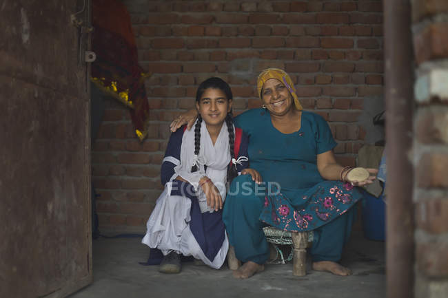 Mulher sentada com sua filha em uniforme escolar — Fotografia de Stock