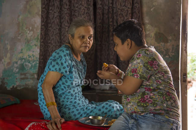 Jeune garçon nourrir sa grand-mère — Photo de stock