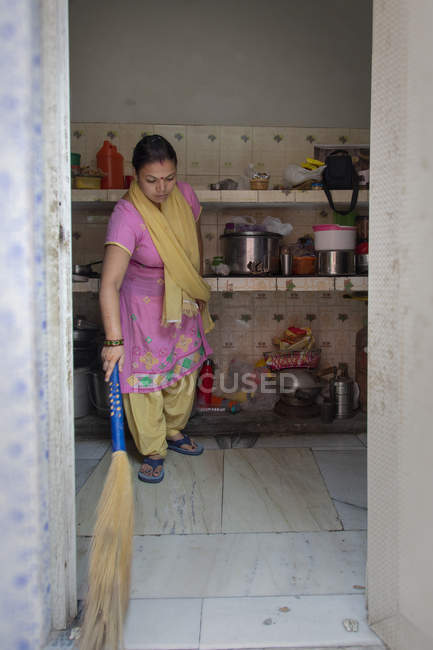 Frau putzt Küche mit Besen — Stockfoto