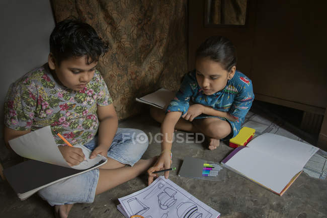 Hermano y hermana dibujando juntos en casa - foto de stock