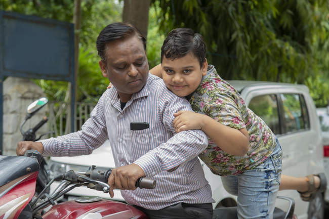 Young boy trying to sit on a bike with his father — Stock Photo