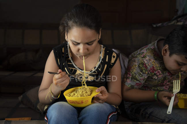 Young brother and sister having noodles — Stock Photo