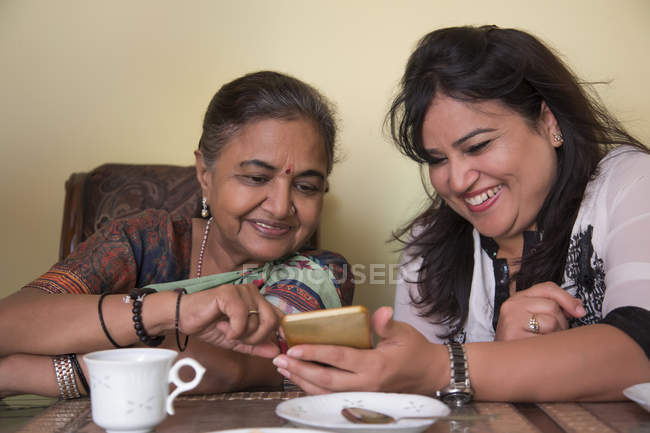 Daughter-in-law showing her phone to her mother-in-law at home. — Stock Photo
