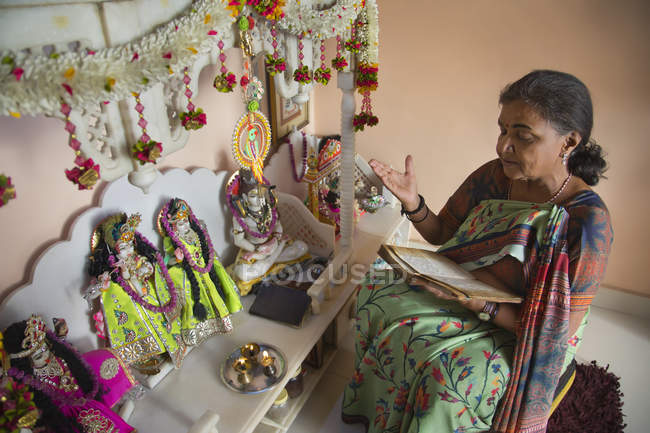 Senior woman reciting prayers during puja at home. — Stock Photo