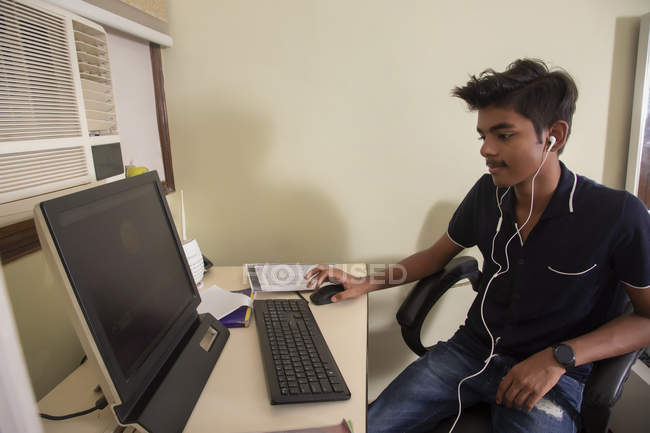 Молодий хлопець сидить перед комп'ютером і навчається вдома . — стокове фото
