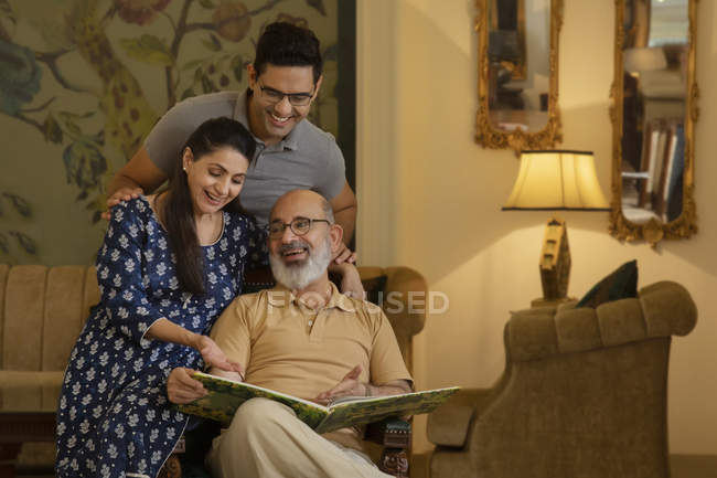 Vater, Mutter und Sohn schauen auf ein Buch und lächeln. (Familie) — Stockfoto