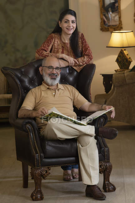 Ein älteres Ehepaar lächelt im Wohnzimmer. — Stockfoto