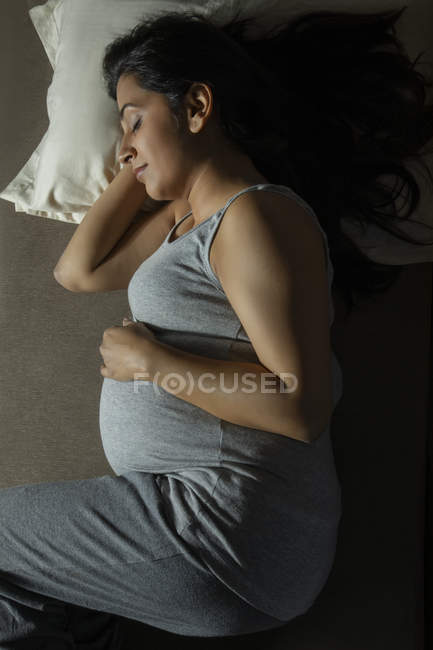 Donna incinta che dorme comodamente sul letto . — Foto stock