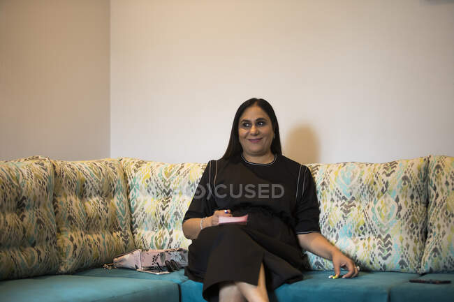 Porträt einer Frau, die bequem auf einer Couch sitzt. — Stockfoto