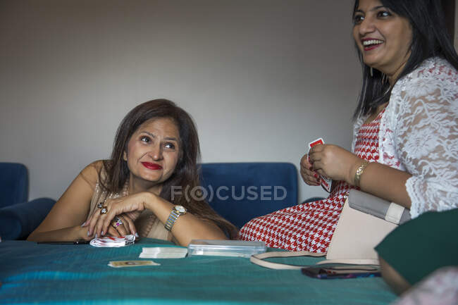 Amigos jugando a las cartas y riendo juntos en una fiesta de gatitos . - foto de stock