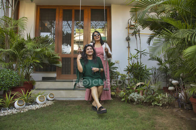 Женщины, стоящие возле качелей на заднем дворе и наслаждающиеся вместе . — стоковое фото