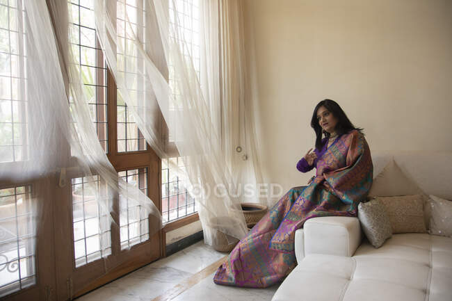 Frau sitzt bequem in ihrem Haus im indischen Anzug. — Stockfoto