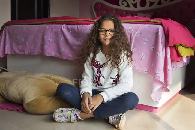 Chica joven sentada en el piso de su dormitorio en casa . - foto de stock