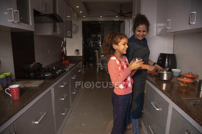 Молода дівчина розділяє сміх зі своєю матір'ю на кухні . — стокове фото