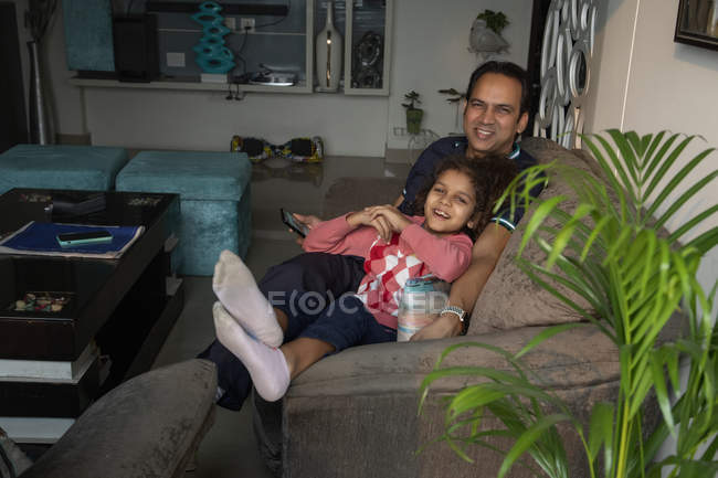 Junges Mädchen ruht sich mit ihrem Vater auf dem heimischen Sofa aus. — Stockfoto