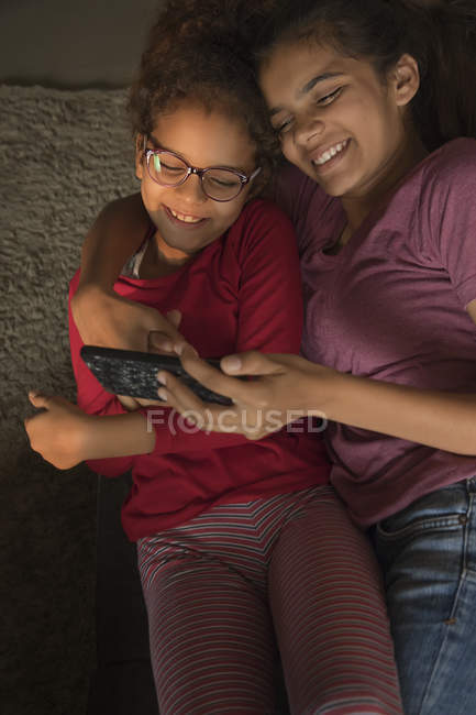 Sisters watching something on the phone together at home. — Stock Photo