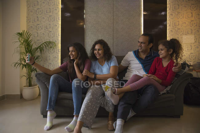Família tirando uma selfie juntos no sofá em casa . — Fotografia de Stock