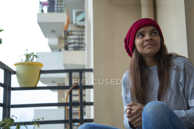 Chica joven sentada en el balcón en una tarde de invierno . - foto de stock