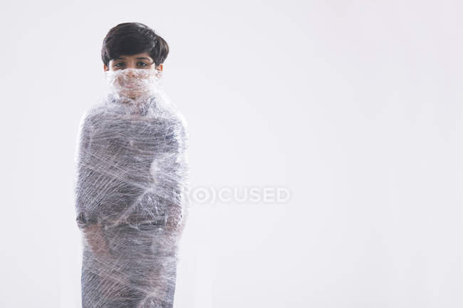 Young boy wrapped in plastic from face to toe unable to breathe. — Stock Photo