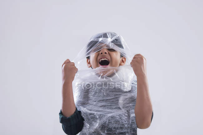 Молодий хлопчик, загорнутий у пластик, не може дихати . — стокове фото