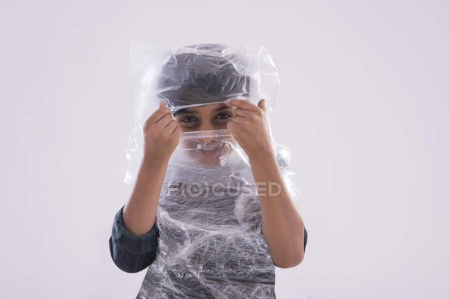 Молодий хлопець намагається подивитися через пластик, загорнутий навколо його обличчя . — стокове фото