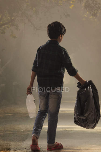 Jeune garçon ramassant des ordures dans les rues et aidant l'environnement . — Photo de stock
