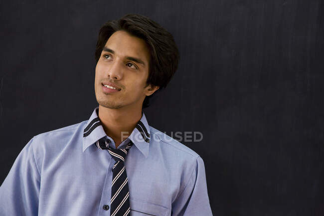 Teenage boy in school uniform standing in front of a blackboard — Stock Photo