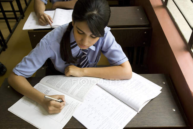 Menina escrevendo em um caderno em uma sala de aula — Fotografia de Stock